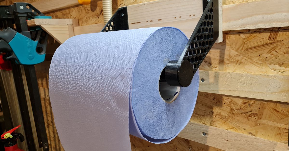 3D printed wall-mounted holder supporting a large workshop paper towel roll above a utility bench