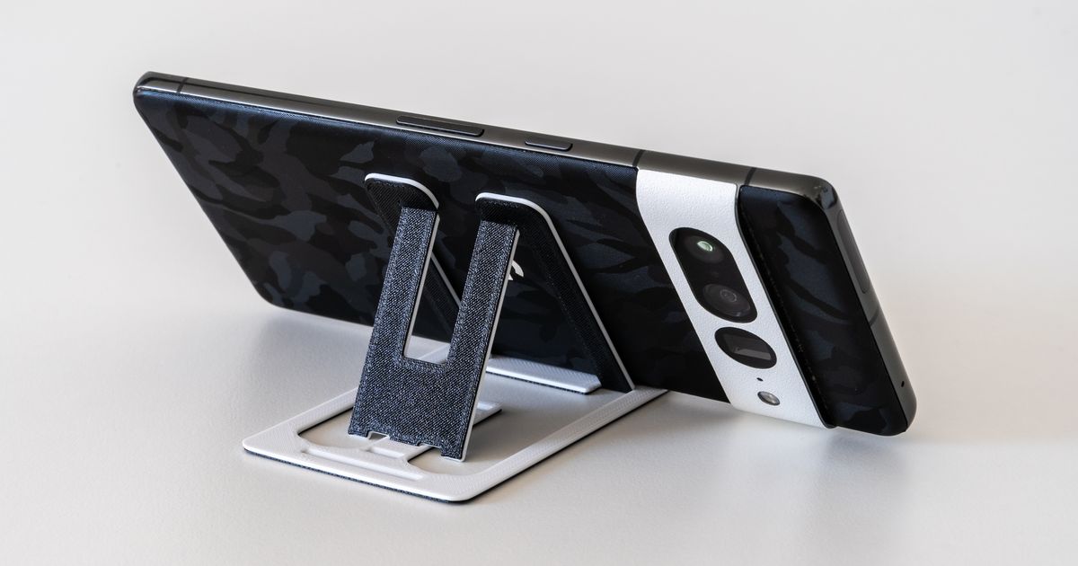 Fold-flat 3D printed phone stand card opened to support a smartphone on a tabletop