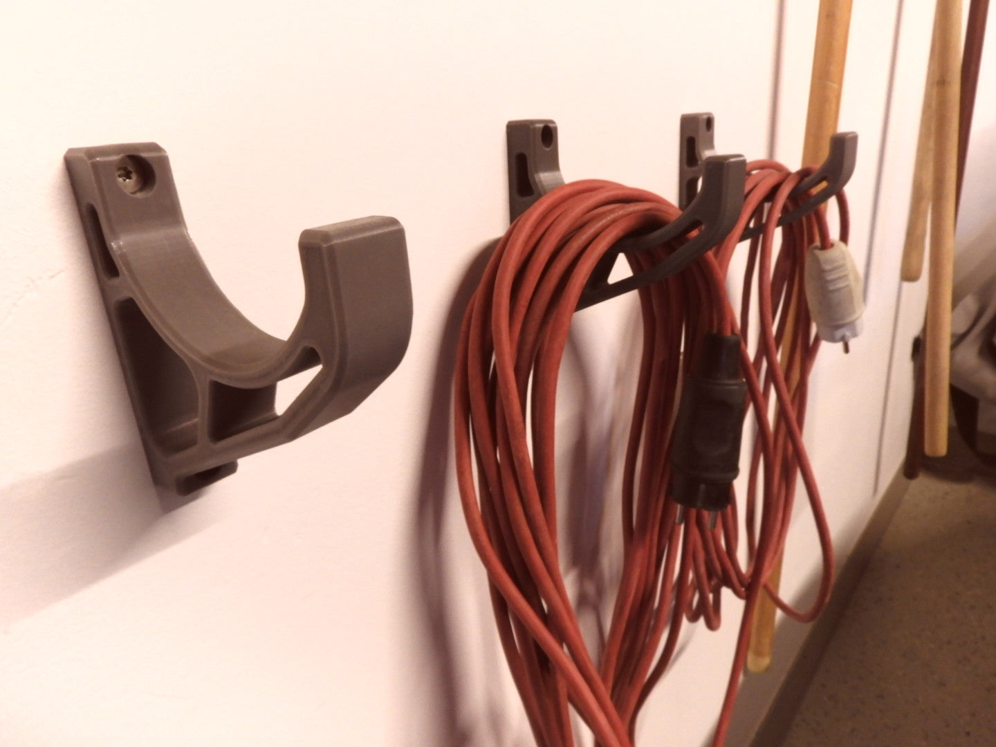 3D printed wall hook holding a coiled extension cord or heavy cable on a workshop wall