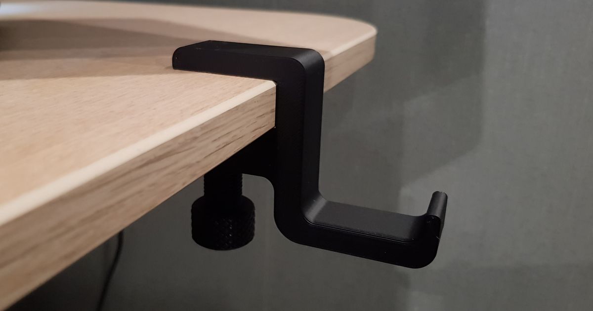 3D printed headset hanger mounted under a desk holding over-ear headphones