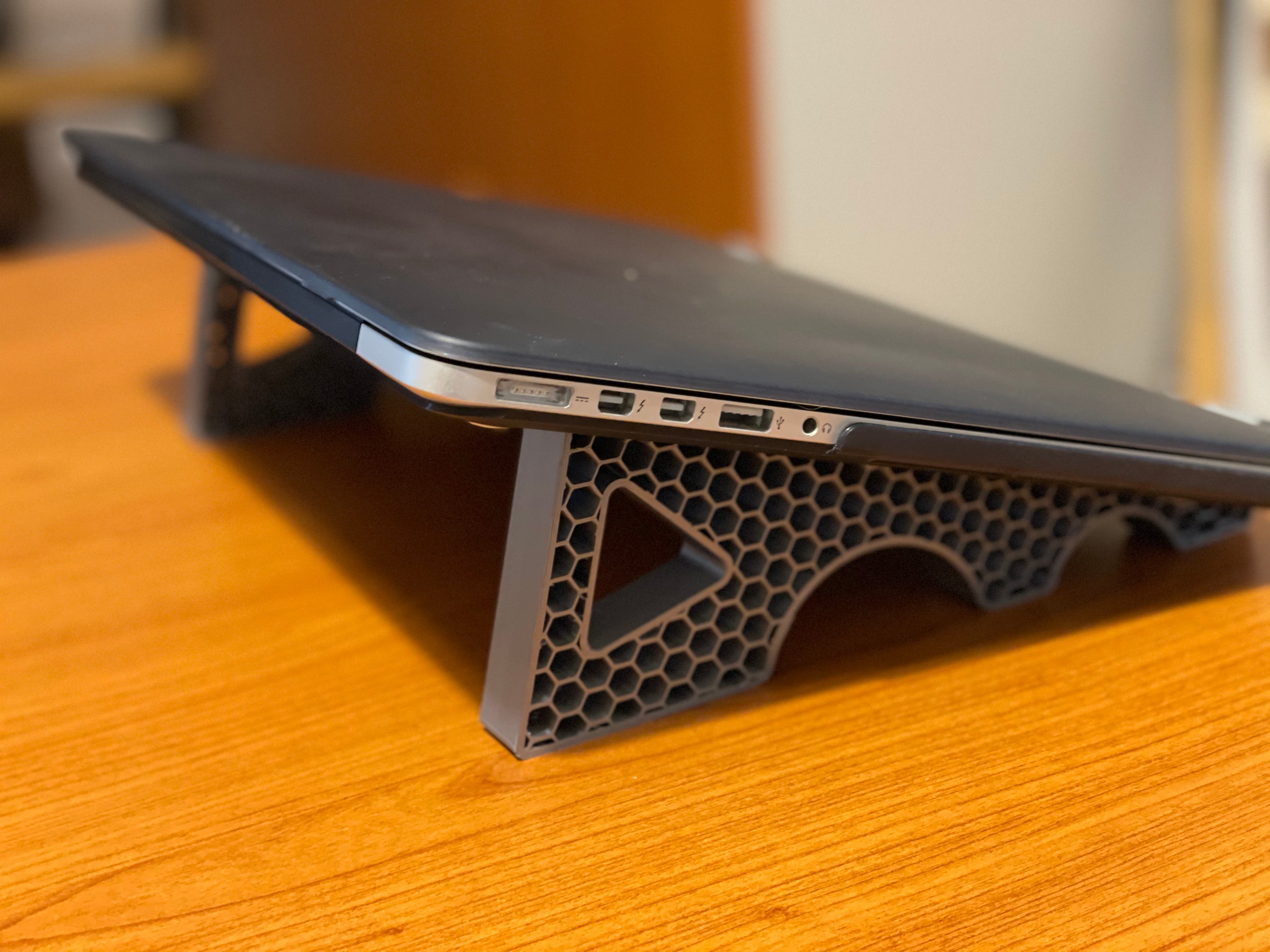 3D printed laptop stand holding a laptop at an ergonomic angle on a desk