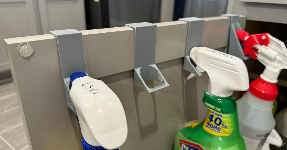 Cabinet door spray bottle holder mounted inside a cabinet door holding cleaning bottles