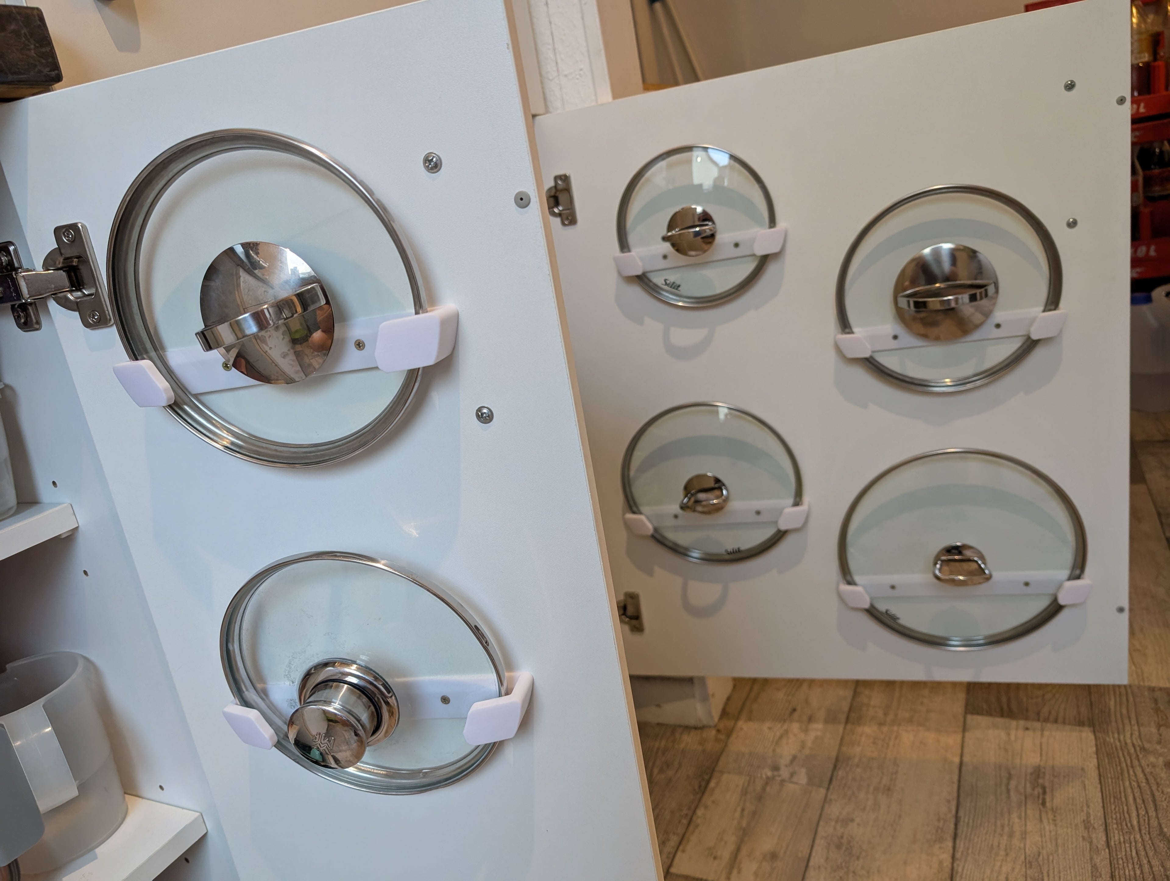 3D printed pot lid holders mounted inside a cabinet door for kitchen lid storage