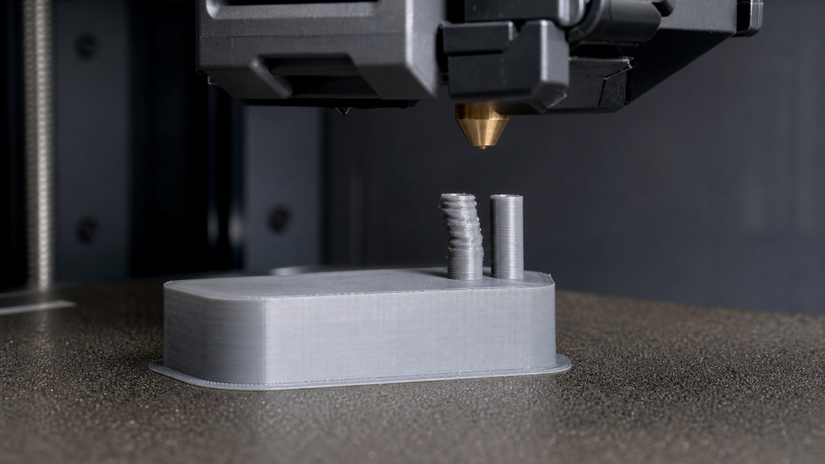Gray FDM calibration print with one small tower melted and leaning beside a clean straight tower